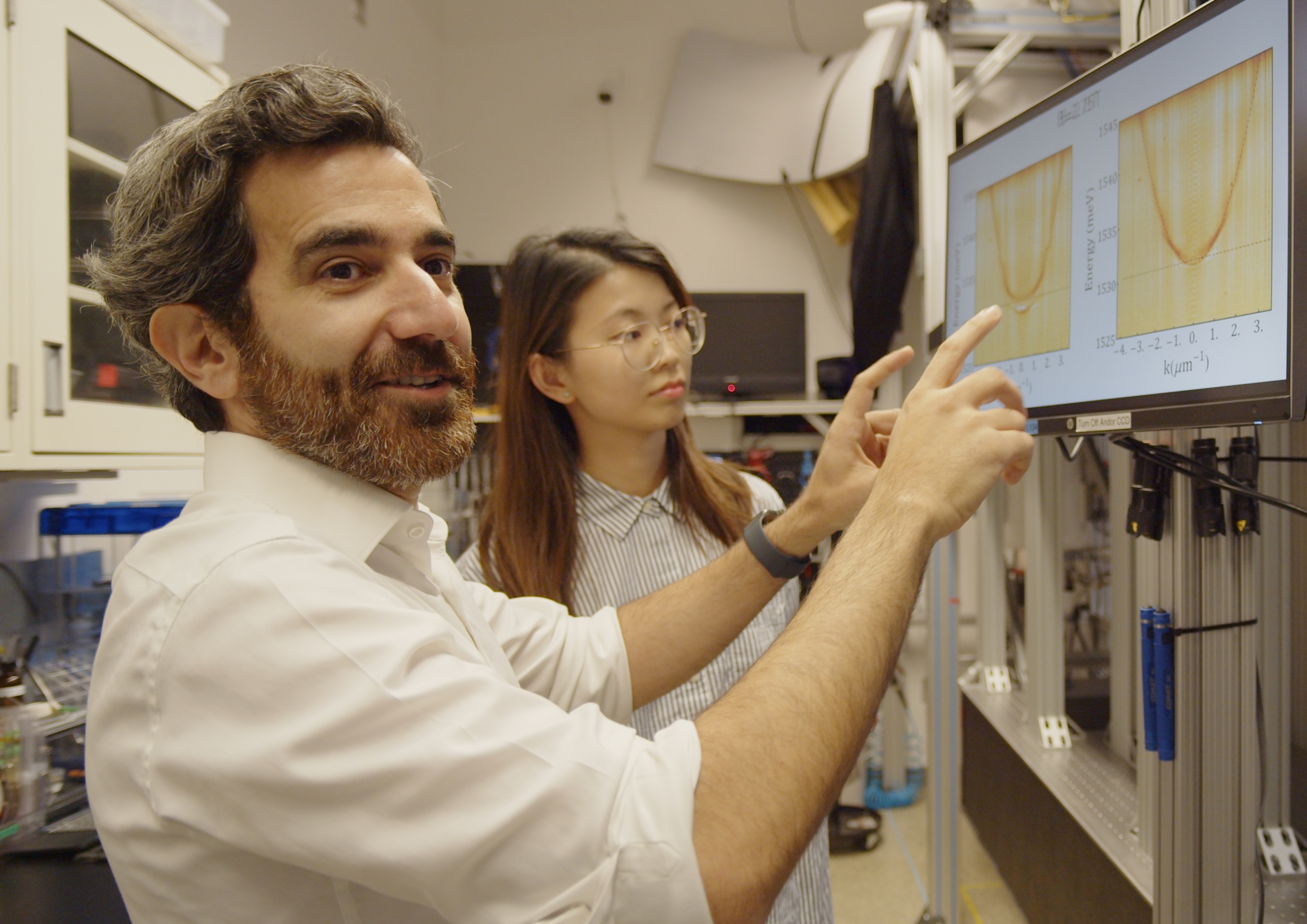Mohammad Hafezi points at data graphs on a monitor while discussing the results with a female colleague in a laboratory.