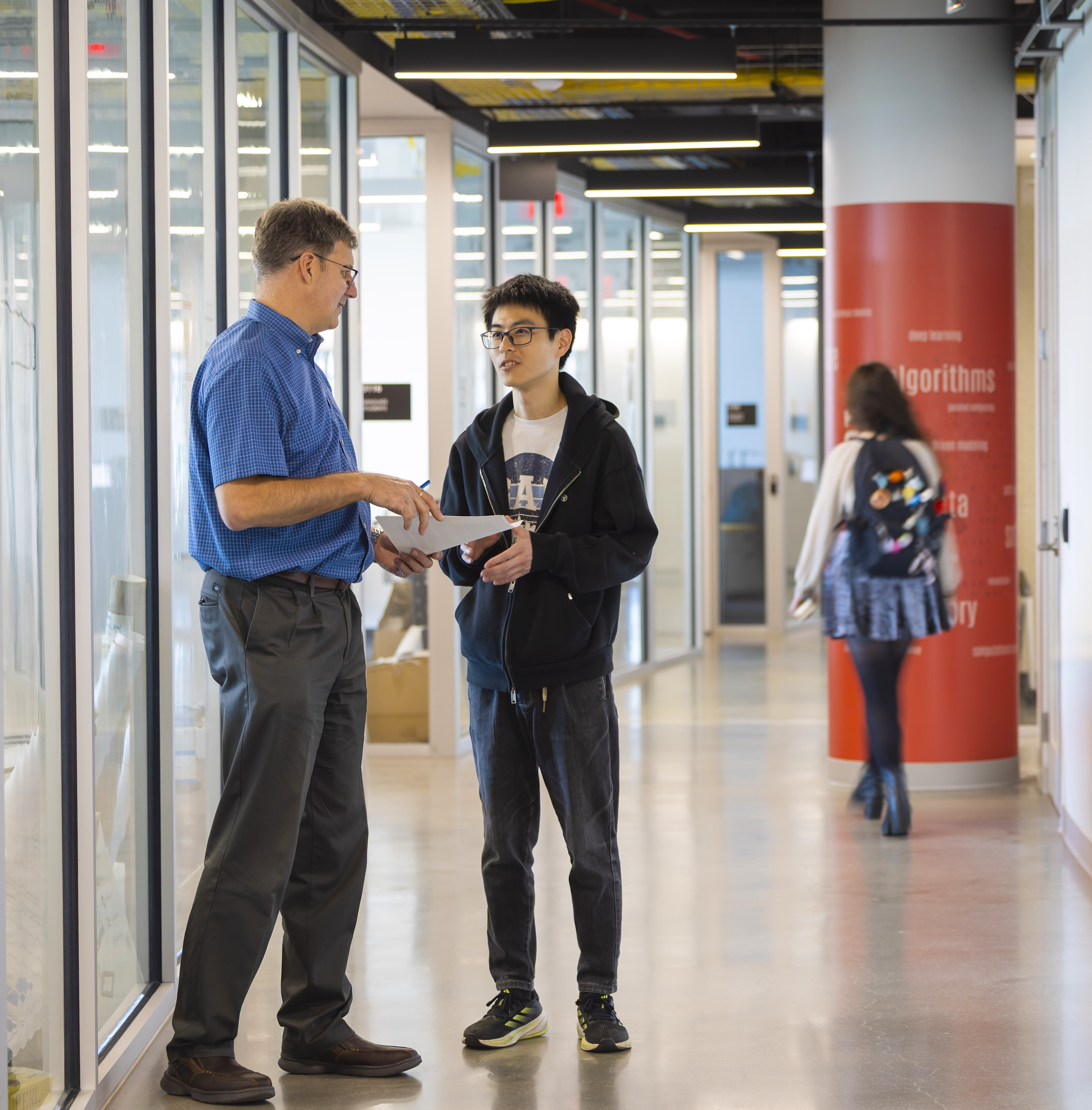 Mihai Pop talking to a student in a corridor