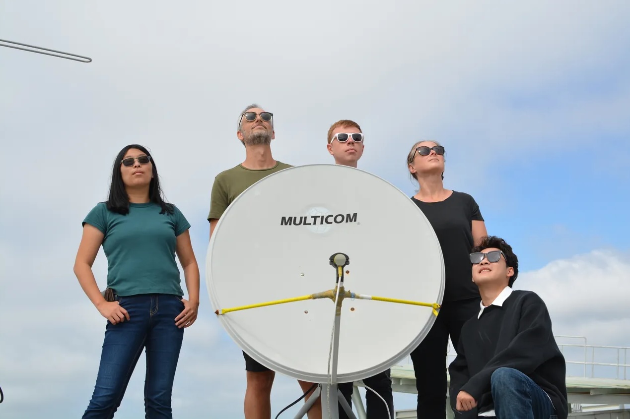 The researchers pose with their satellite receiver system on the roof of a university building in San Diego.