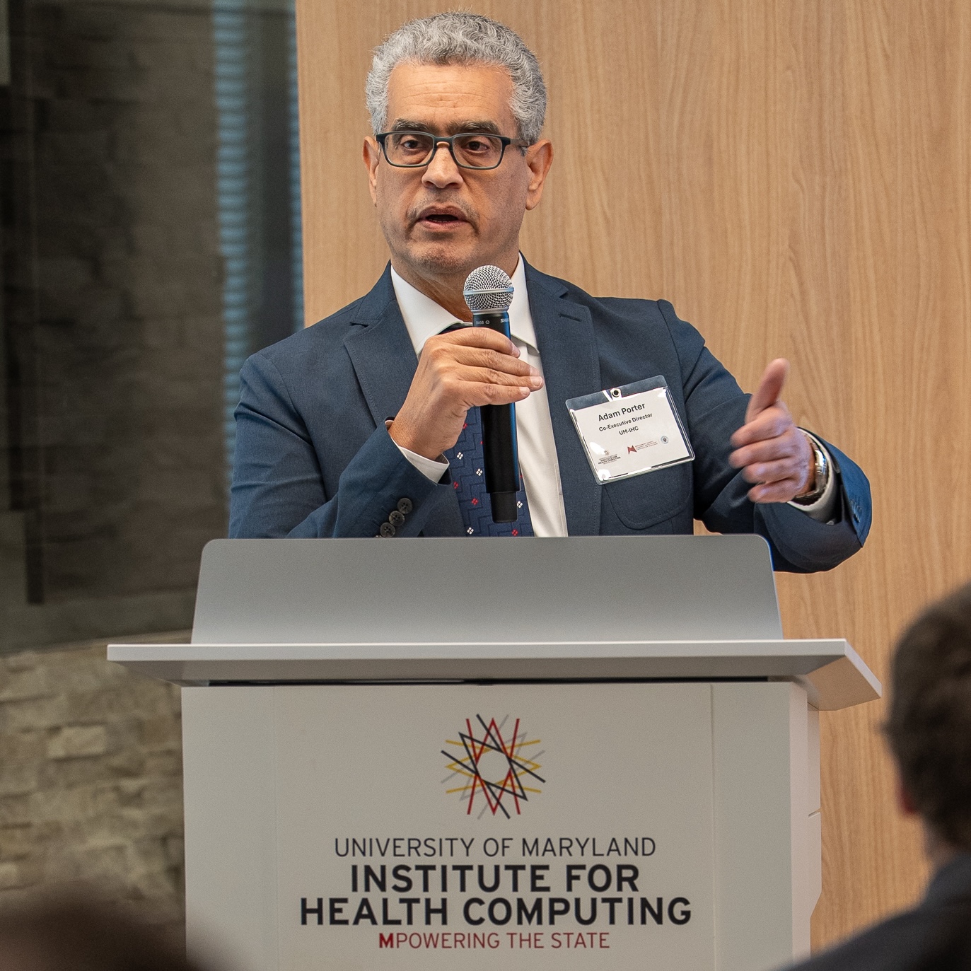 Adam speaking ad IHC podium with microphone