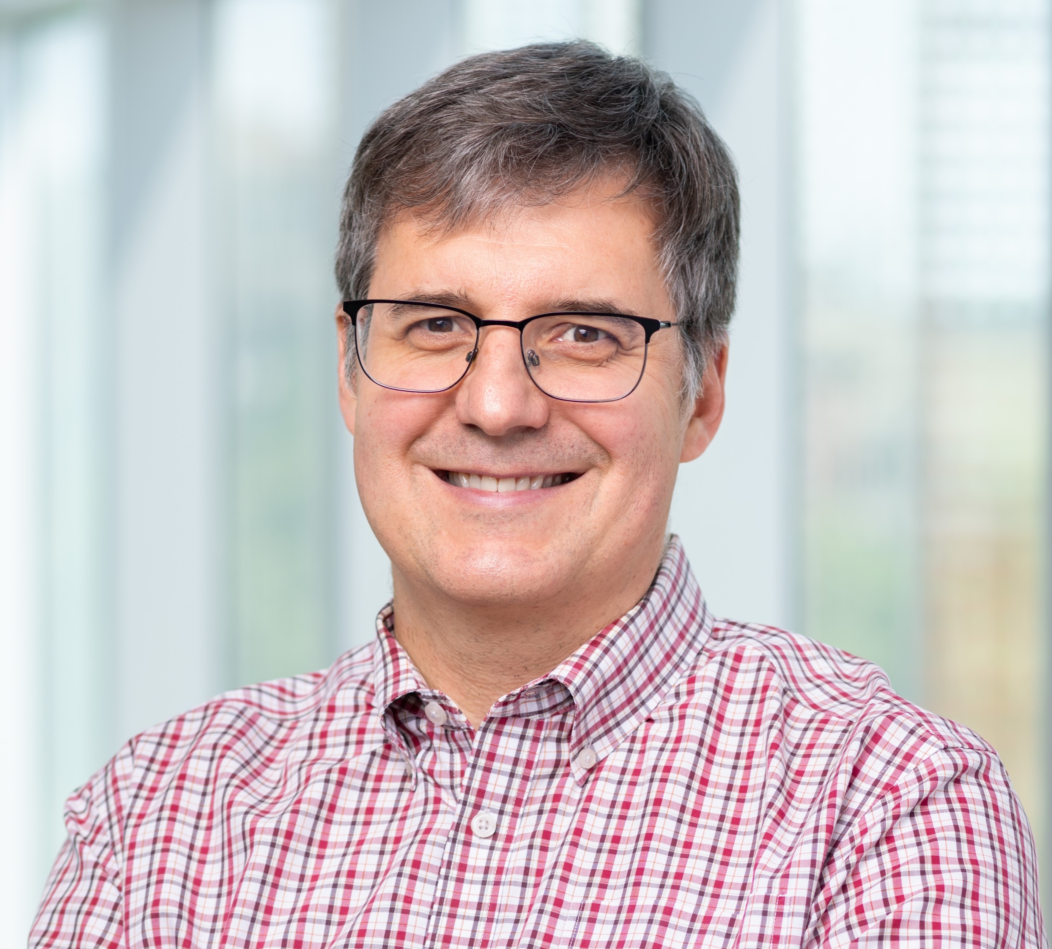 man in red plaid shirt and black glasses smiling