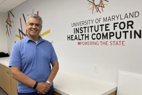Adam Porter stands in front of the logo for the University of Maryland Institute for Health Computing.