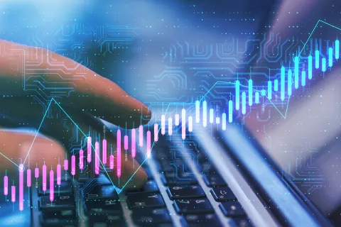 A close-up view of a person's hands typing on a laptop keyboard, overlaid with a glowing digital graphic of a rising financial stock chart, data points, and circuit board patterns in shades of blue, pink, and turquoise.