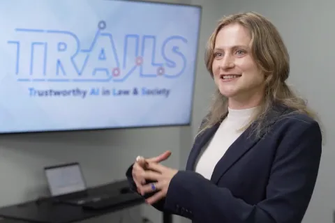 Laura Fichtner talking and smiling in front of TRAILS logo