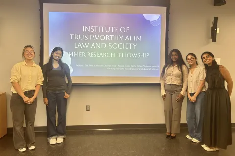 five women stand in front of projection of their final presentation