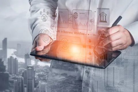 A double-exposure image of a professional holding a tablet and stylus, interacting with glowing digital icons representing "AI in Business Workflow," data analytics, and cloud storage, with a cityscape superimposed in the background.