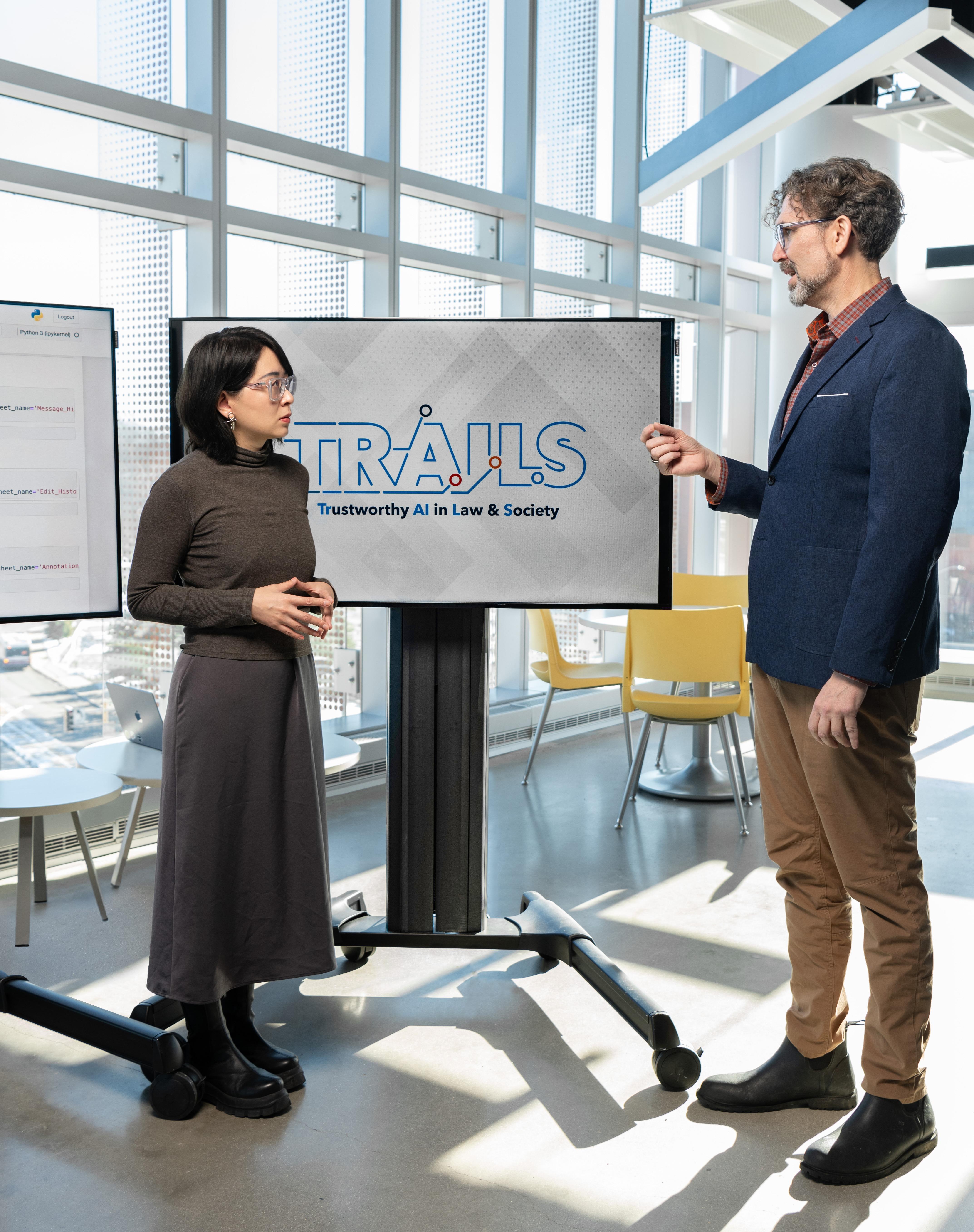 man and woman talking in front of TRAILS logo