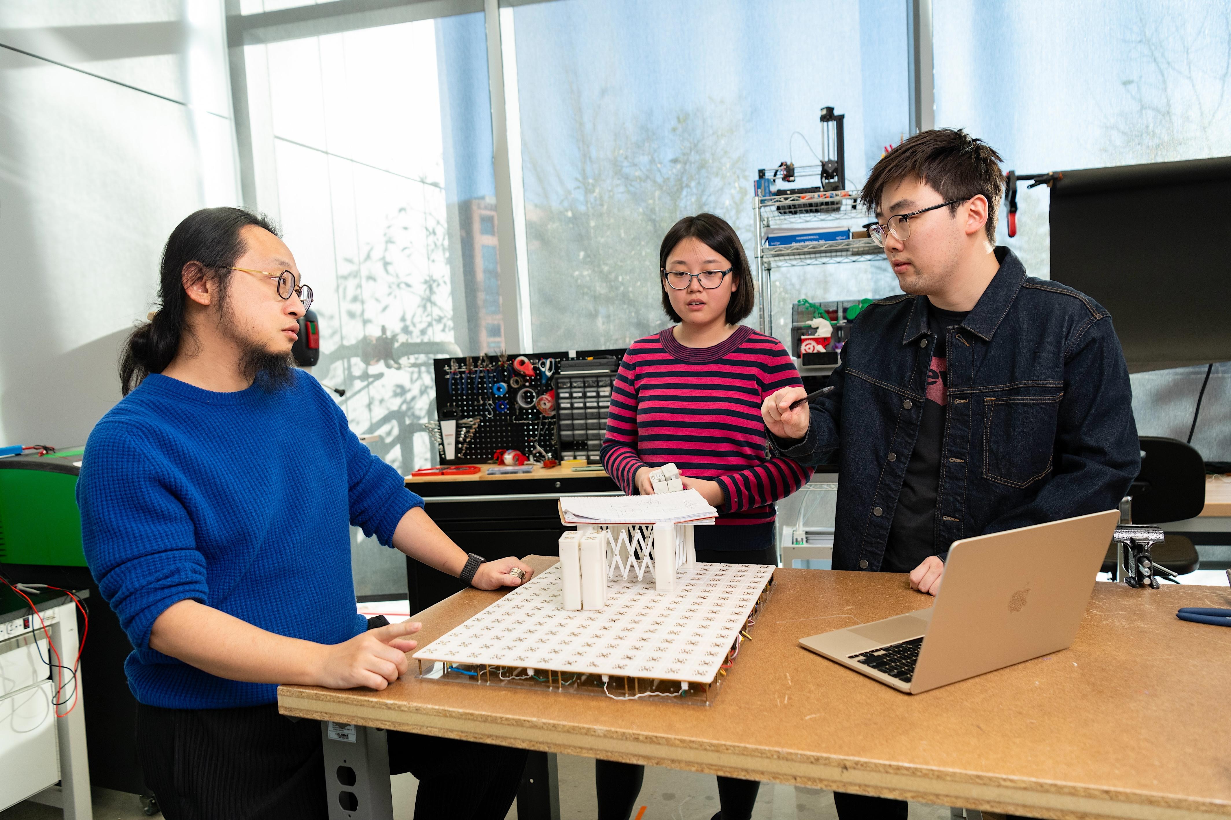 Working in his Small Artifacts (SMART) Lab, Assistant Professor of Computer Science Huaishu Peng and doctoral students Zining Zhang (center) and Jiasheng Li (right) discuss technology that can assist sight-impaired people.