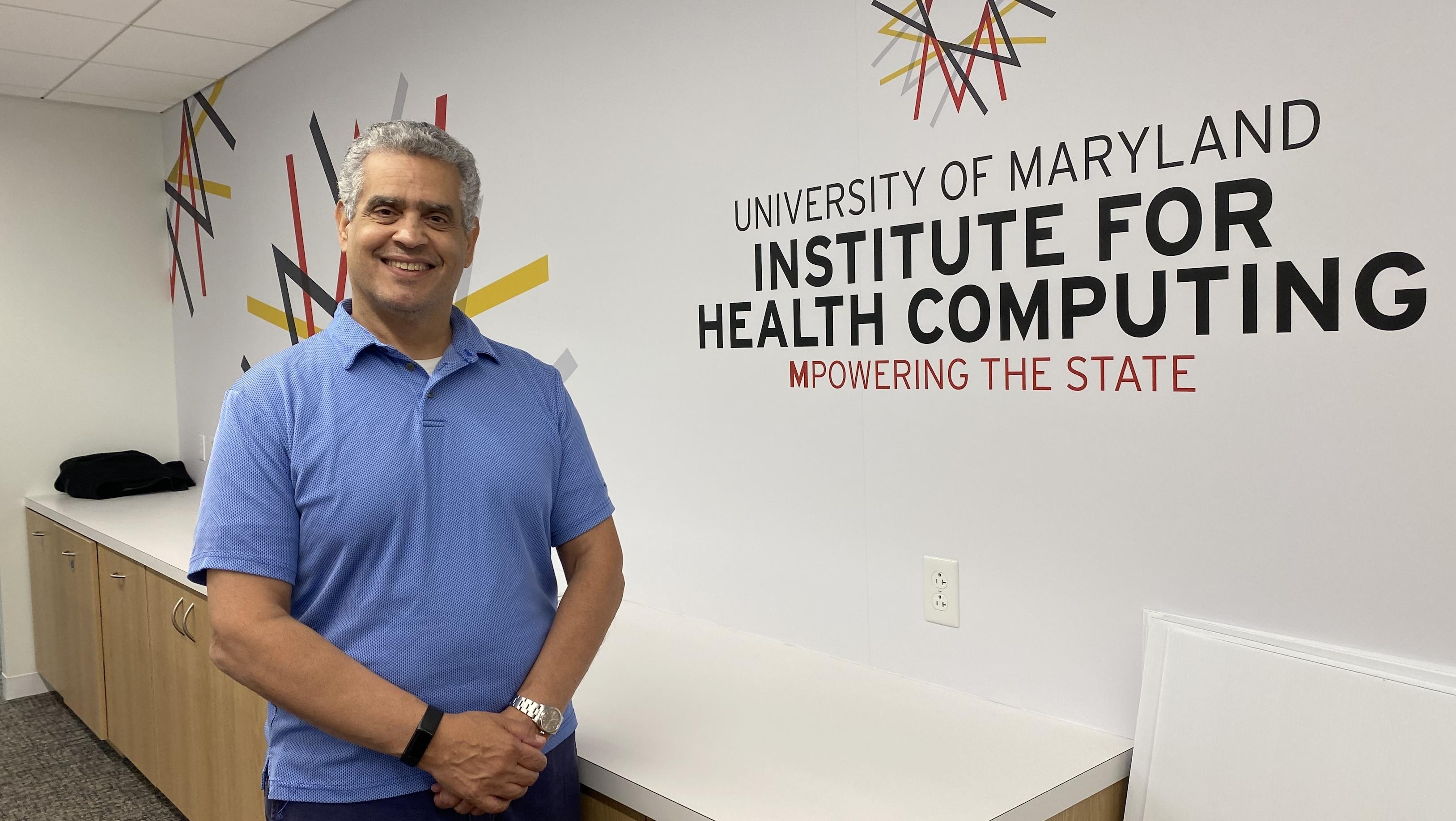 Adam Porter stands in front of the logo for the University of Maryland Institute for Health Computing.