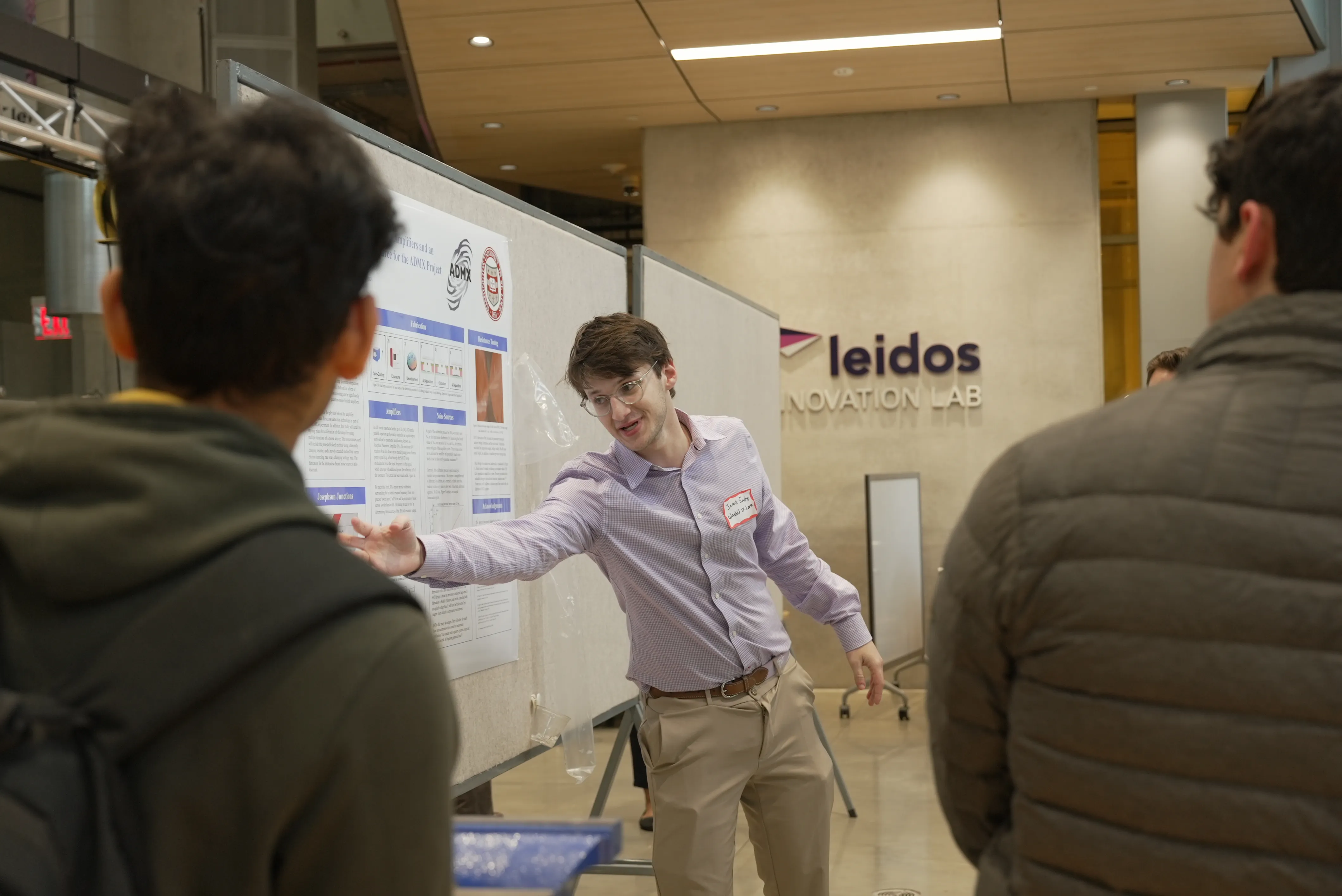 man presenting research poster with leidos logo in background