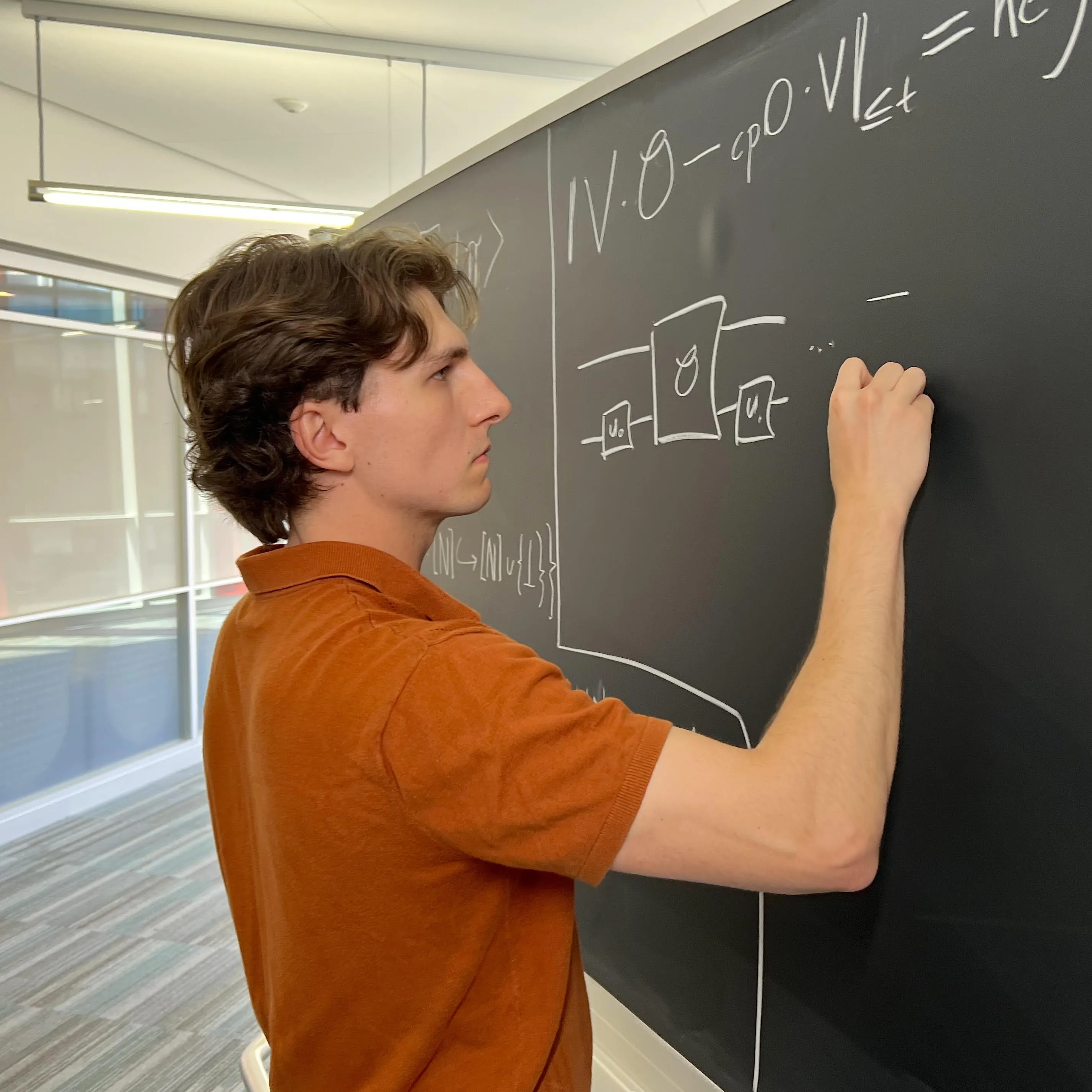 Joseph Carolan writes equations in chalk on a blackboard.