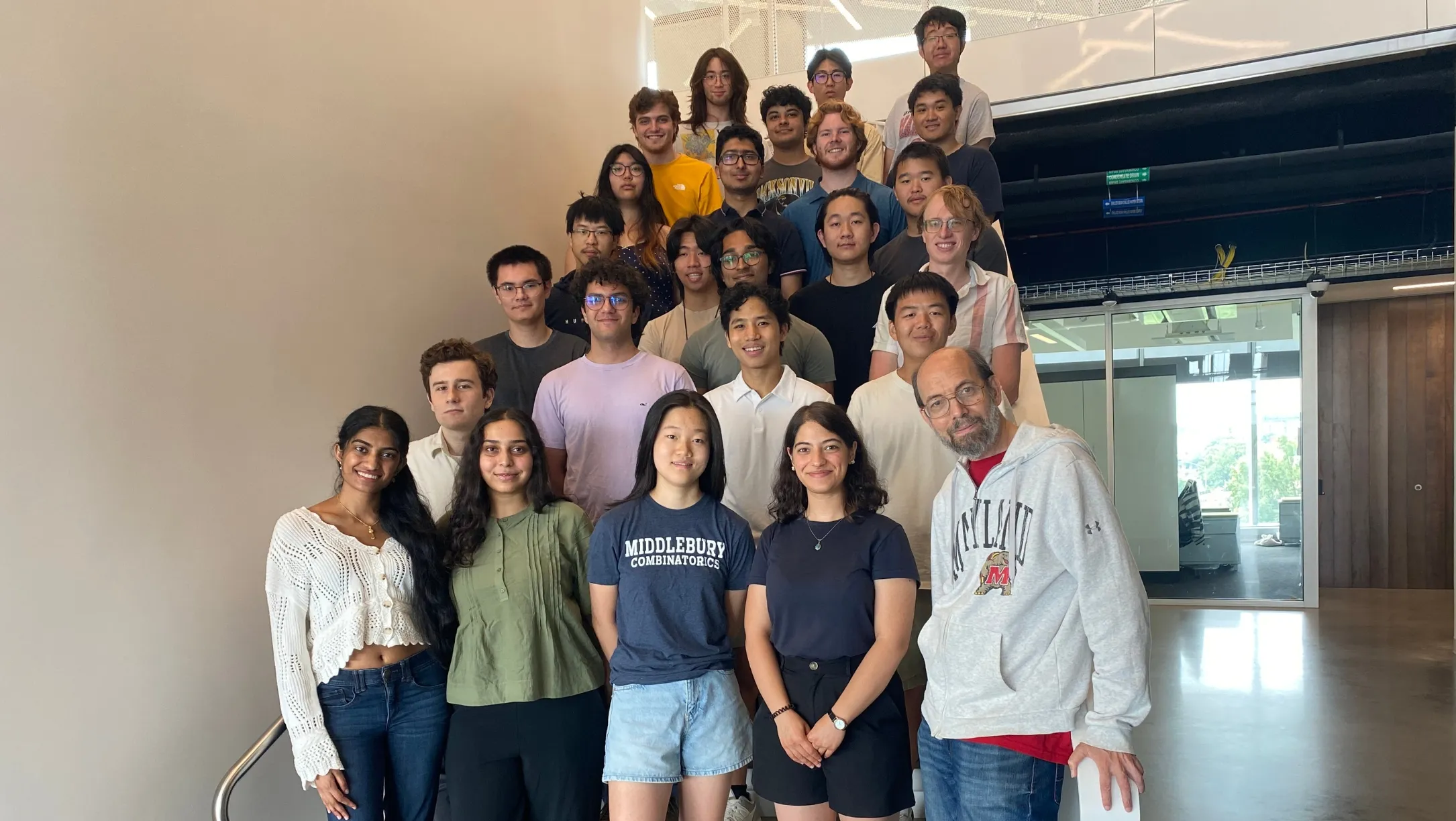 Participants in the 2025 REU-CAAR program gather on a staircase with principal investigator William Gasarch (front right) at the University of Maryland.