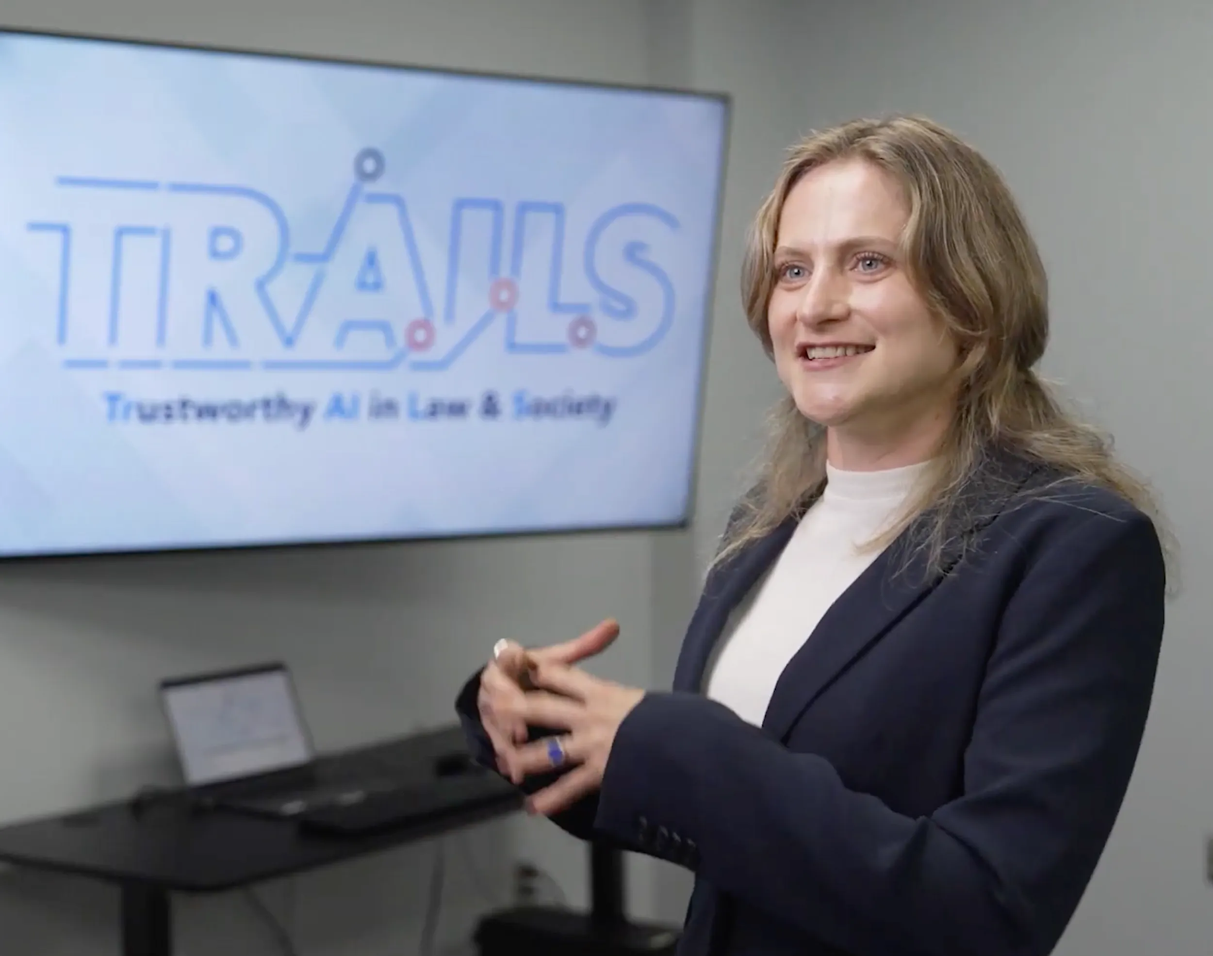 Laura Fichtner talking and smiling in front of TRAILS logo