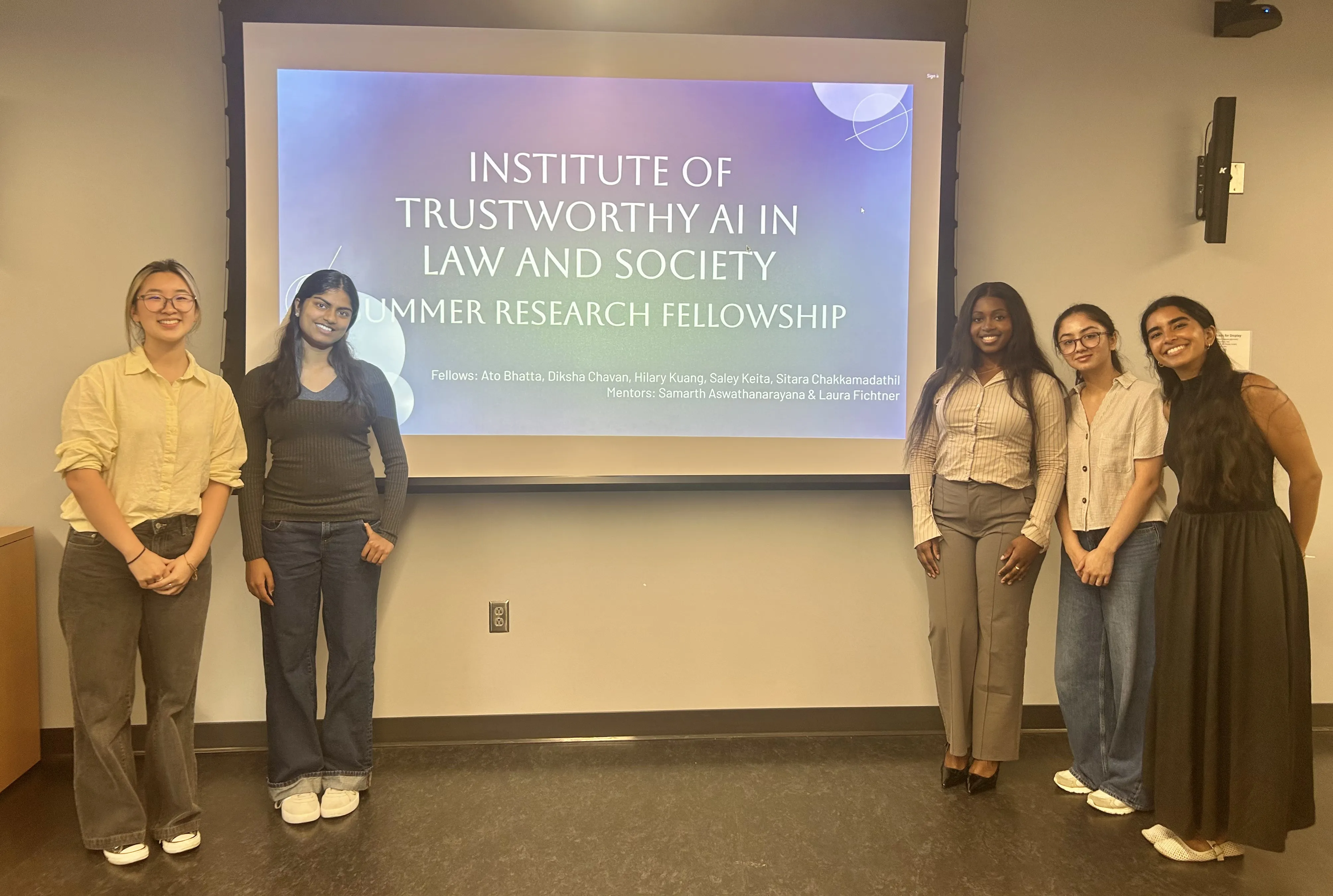 five women stand in front of projection of their final presentation