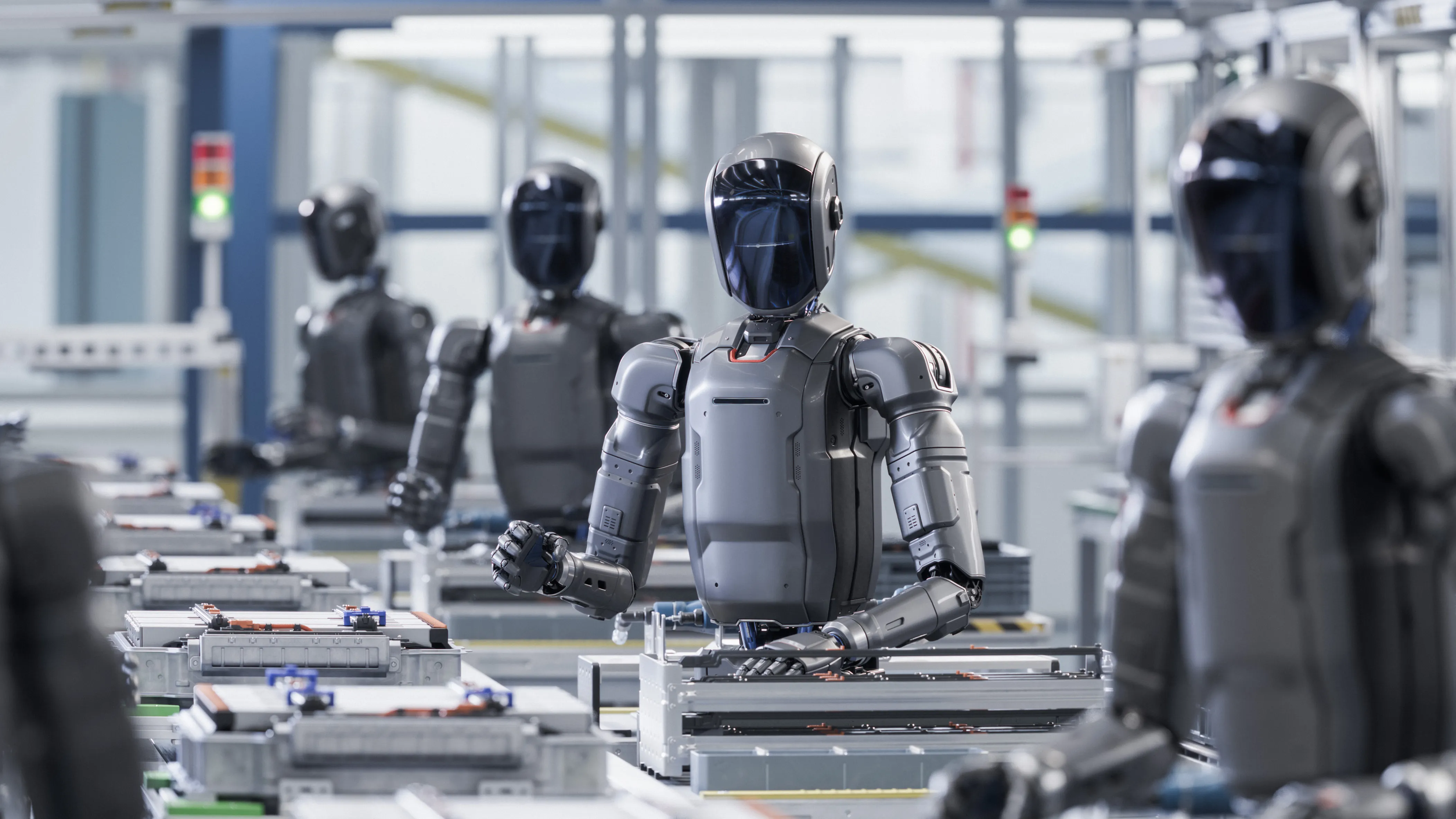 A line of sleek, dark gray humanoid robots working on an assembly line in a modern, high-tech manufacturing factory.